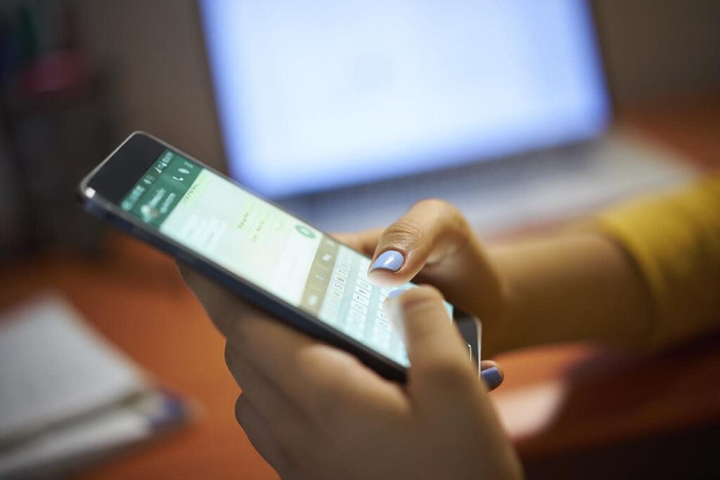 Young woman using whatsapp to message a company